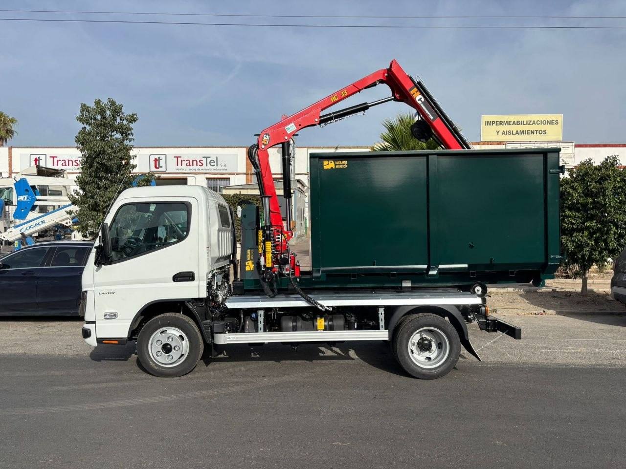 Camión equipado con sistema multigancho, caja tipo poda de color verde y grúa autocarga roja